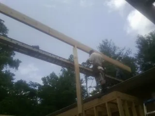 Carpenter setting a ridge beam over a new addition frame — Ice Dam Removal by Roofing Brothers in Logan