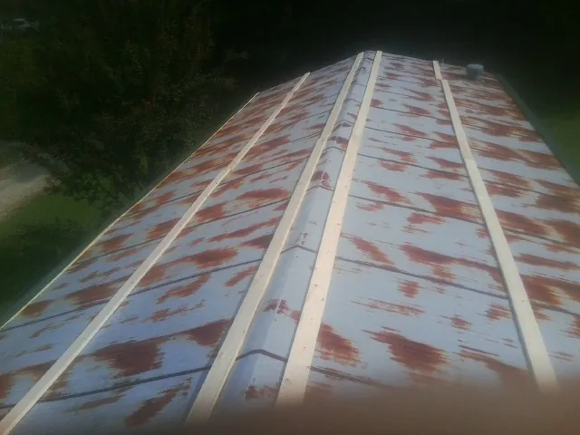 Rusted metal roof panels with new wood purlins before replacement — Storm Damage Roof Repair in Logan by Roofing Brothers